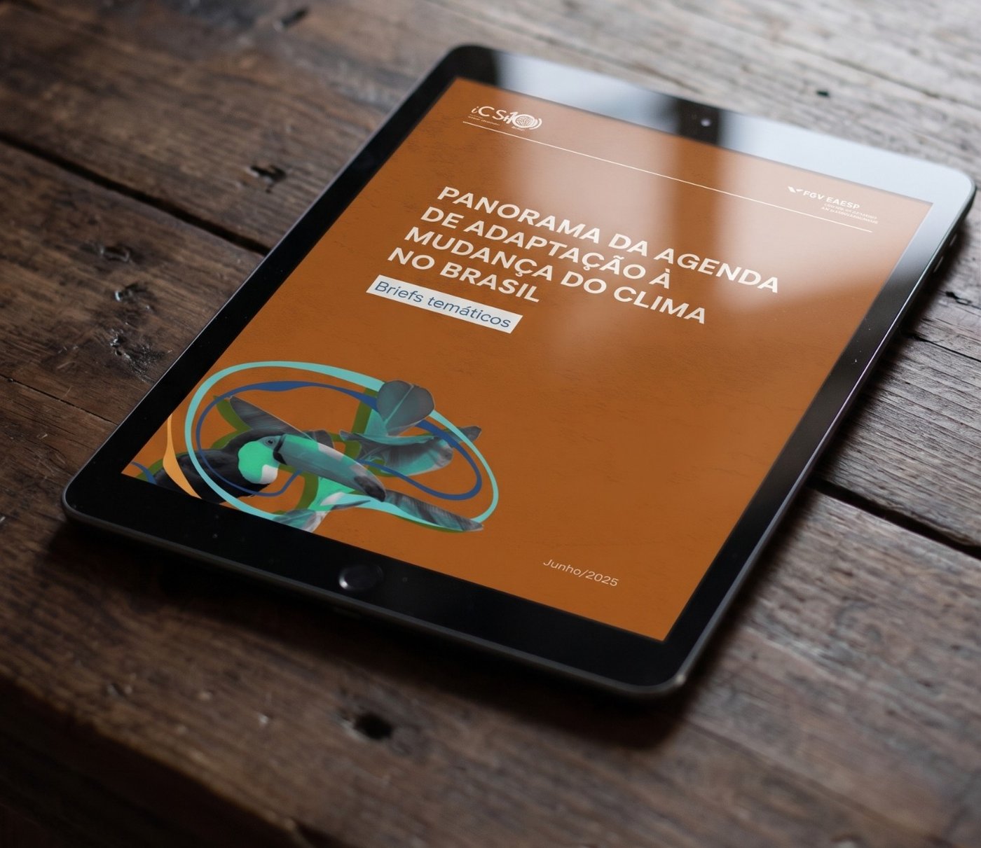 Tablet on a wooden table showing the cover of the material Overview of the Climate Change Adaptation Agenda in Brazil: thematic briefs